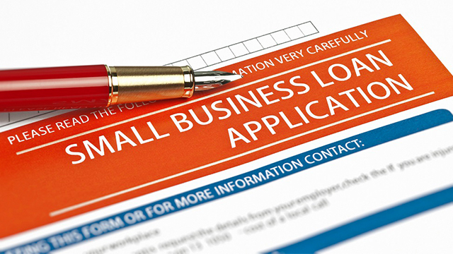 Red pen ontop of a white Small Business Loan Application